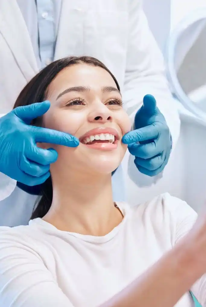 Dentist in blue gloves examining patient's teeth during dental checkup in clinical office.